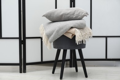 Photo of Woolen blankets and pillow on pouf indoors