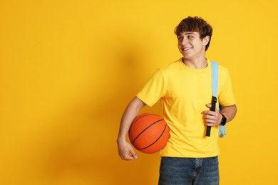 Photo of Teenage boy with basketball on yellow background. Space for text