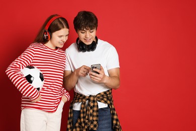 Photo of Teenage boy showing his friend something on smartphone against red background. Space for text