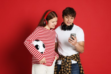 Photo of Teenage boy showing his friend something on smartphone against red background