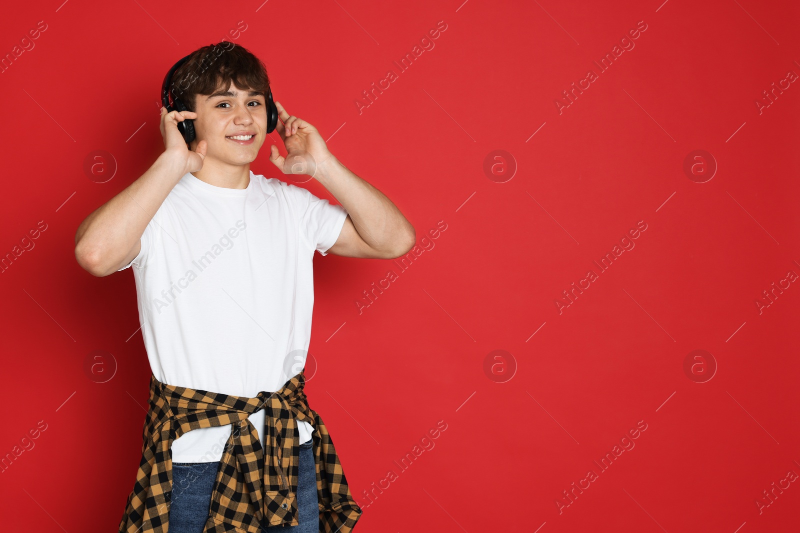 Teenage boy listening to music on red background. Space for text Photo of Teenage boy listening to music on red background. Space for text