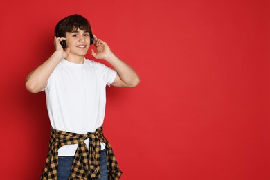 Photo of Teenage boy listening to music on red background. Space for text