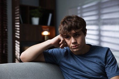 Photo of Teen problems. Upset teenage boy on sofa at home