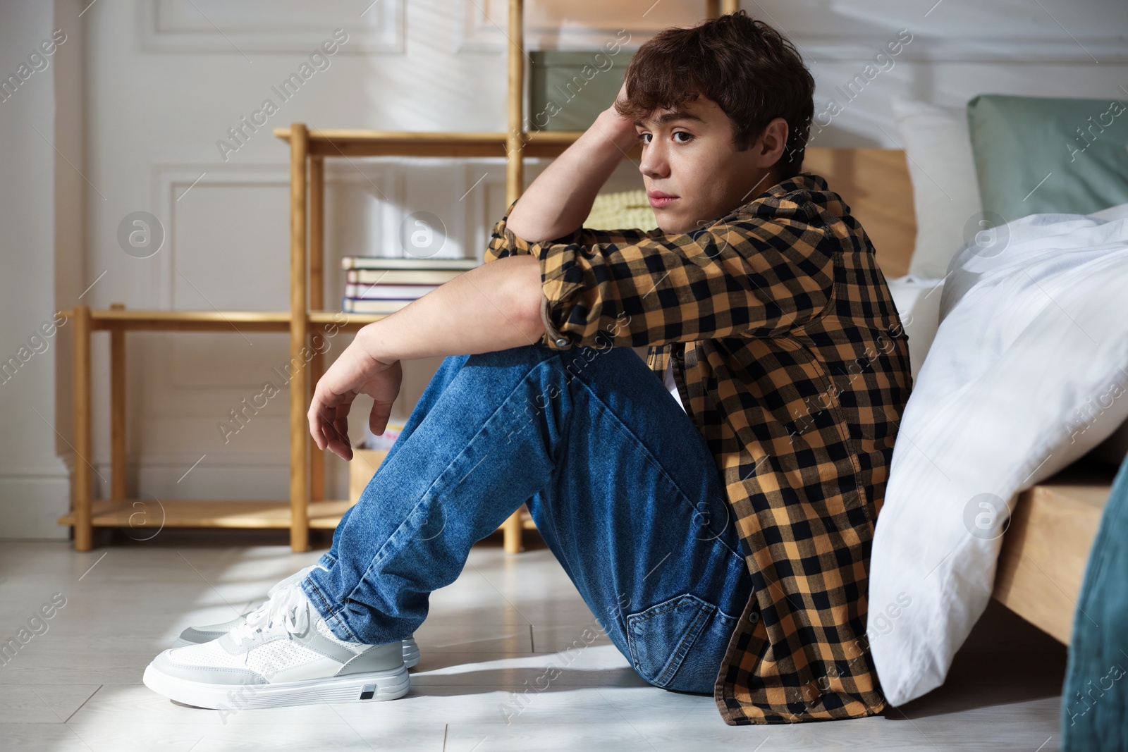Teen problems. Depressed teenage boy near bed at home Photo of Teen problems. Depressed teenage boy near bed at home