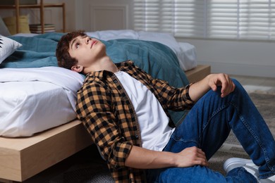 Photo of Teen problems. Upset teenage boy on floor at home