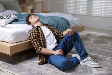 Photo of Teen problems. Upset teenage boy on floor at home