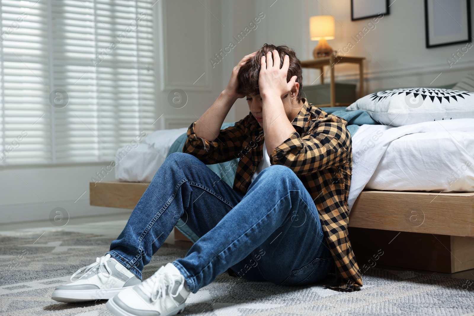 Teen problems. Depressed teenage boy on floor at home Photo of Teen problems. Depressed teenage boy on floor at home