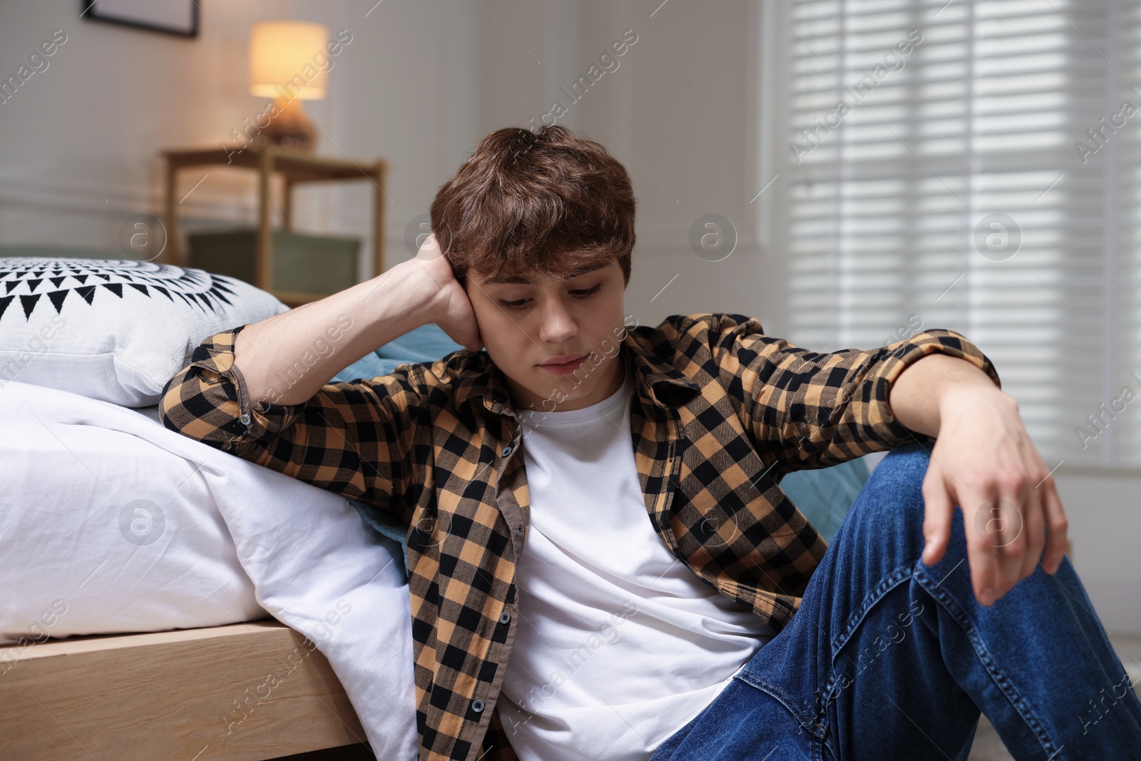 Teen problems. Upset teenage boy on floor at home Photo of Teen problems. Upset teenage boy on floor at home