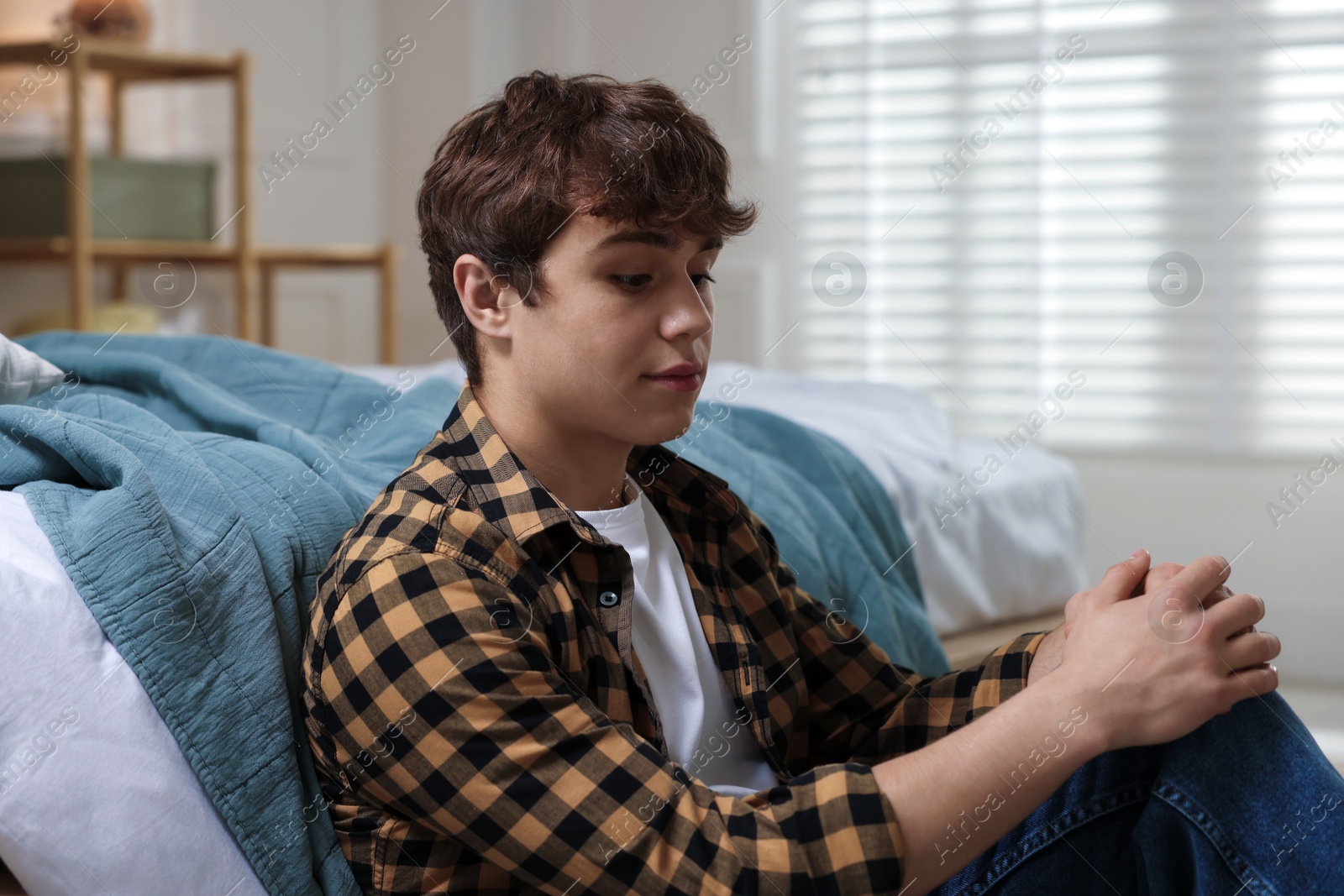 Teen problems. Upset teenage boy on floor at home Photo of Teen problems. Upset teenage boy on floor at home