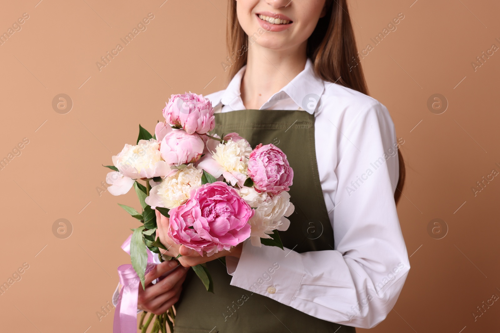 Florist with beautiful bouquet of peonies on dark beige background, closeup Photo of Florist with beautiful bouquet of peonies on dark beige background, closeup