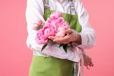 Photo of Florist with beautiful bouquet of peonies on pink background, closeup