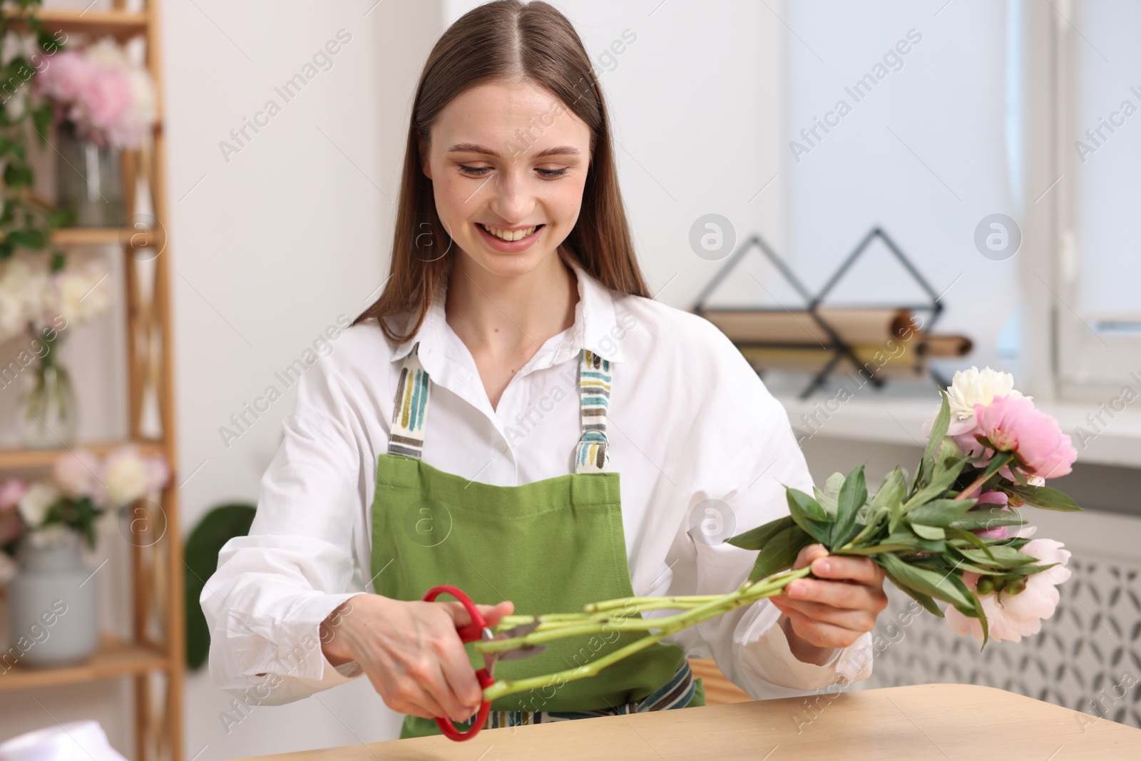 Florist making bouquet of peonies at table in flower shop Photo of Florist making bouquet of peonies at table in flower shop
