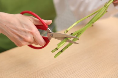 Photo of Florist making bouquet of flowers at wooden table, closeup