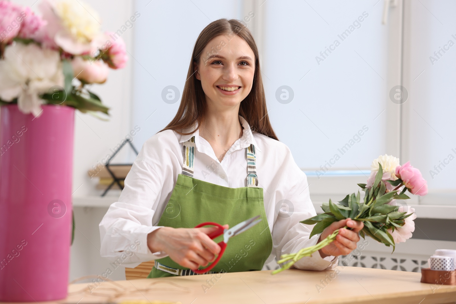Florist making bouquet of peonies at table in flower shop Photo of Florist making bouquet of peonies at table in flower shop