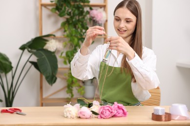 Photo of Florist making bouquet of peonies at wooden table in flower shop, space for text