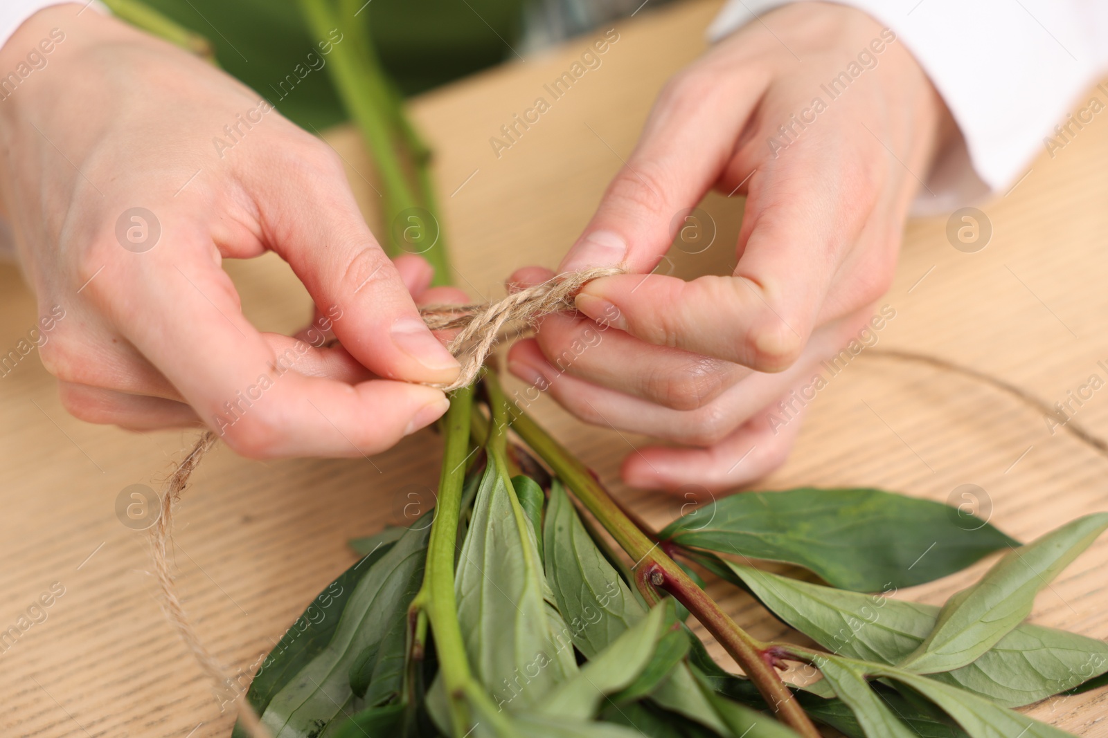 Florist making bouquet of flowers at wooden table, closeup Photo of Florist making bouquet of flowers at wooden table, closeup