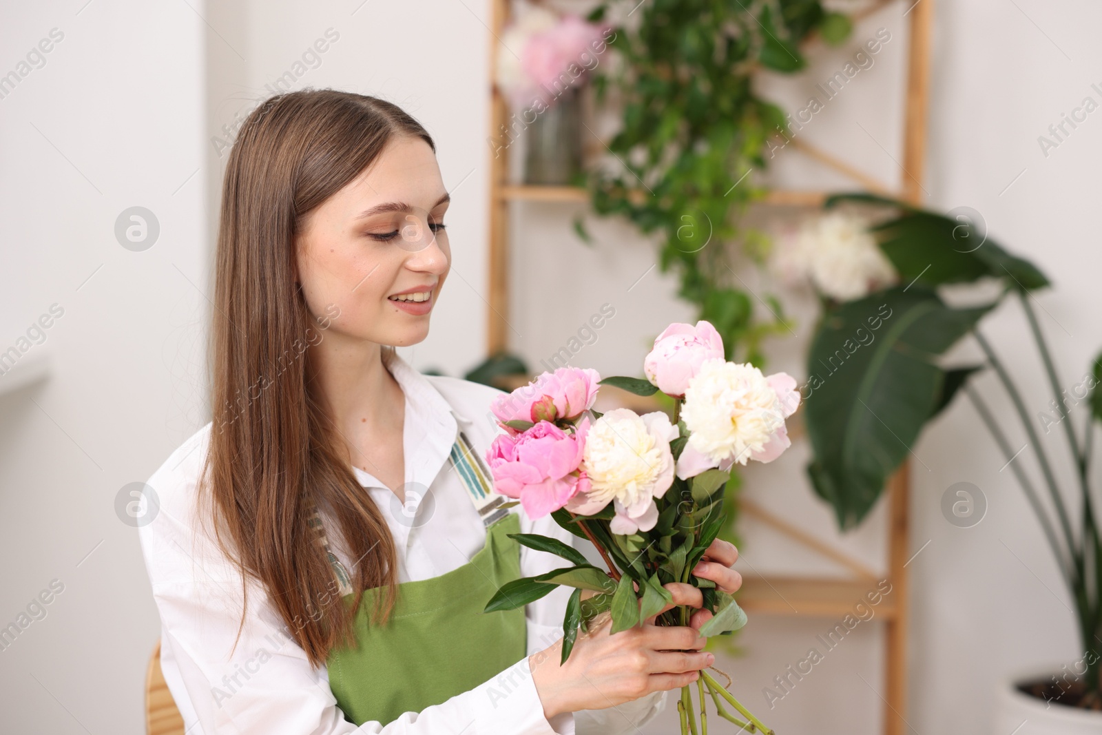 Florist with bouquet of peonies in flower shop Photo of Florist with bouquet of peonies in flower shop