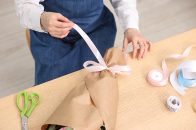 Photo of Florist making bouquet of flowers at wooden table in flower shop, above view