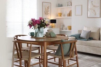 Photo of Dining table with beautiful flowers and dishware in room. Interior design