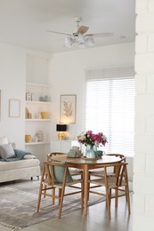 Photo of Dining table with beautiful flowers and dishware in room, space for text. Interior design