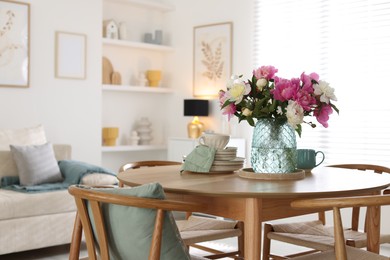 Photo of Dining table with beautiful flowers and dishware in room, space for text. Interior design