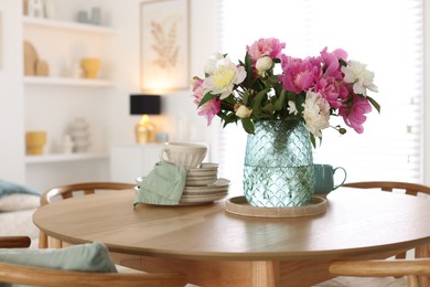 Photo of Dining table with beautiful flowers and dishware in room, space for text. Interior design