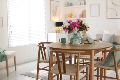 Photo of Dining table with beautiful flowers and dishware in room. Interior design
