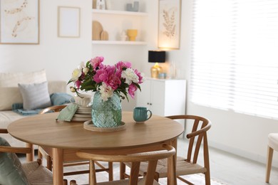 Photo of Dining table with beautiful flowers and dishware in room. Interior design