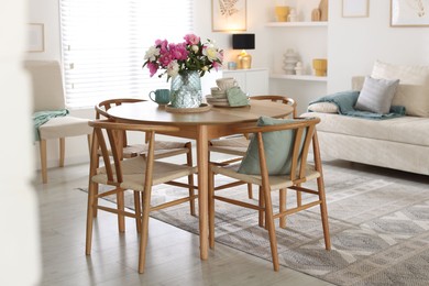 Photo of Dining table with beautiful flowers and dishware in room. Interior design