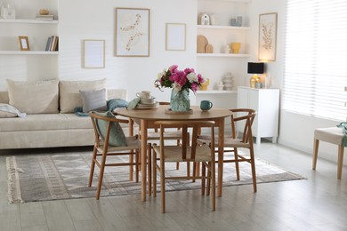 Photo of Dining table with beautiful flowers and dishware in room. Interior design