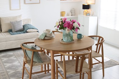 Photo of Dining table with beautiful flowers and dishware in room. Interior design