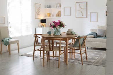 Photo of Dining table with beautiful flowers and dishware in room. Interior design