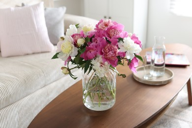 Photo of Bouquet of beautiful peonies and water on coffee table indoors. Interior design