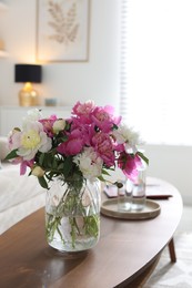 Photo of Bouquet of beautiful peonies and water on coffee table indoors. Interior design
