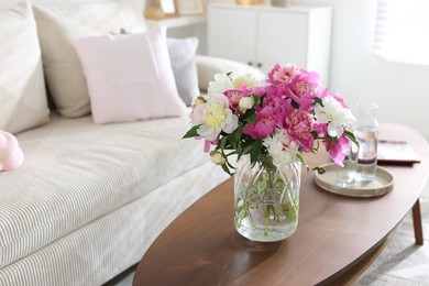 Photo of Bouquet of beautiful peonies and water on coffee table indoors, space for text. Interior design