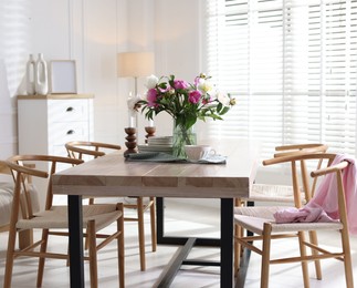 Photo of Dining table with beautiful flowers and dishware in room. Interior design