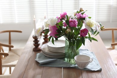 Photo of Dining table with beautiful flowers and dishware in room. Interior design