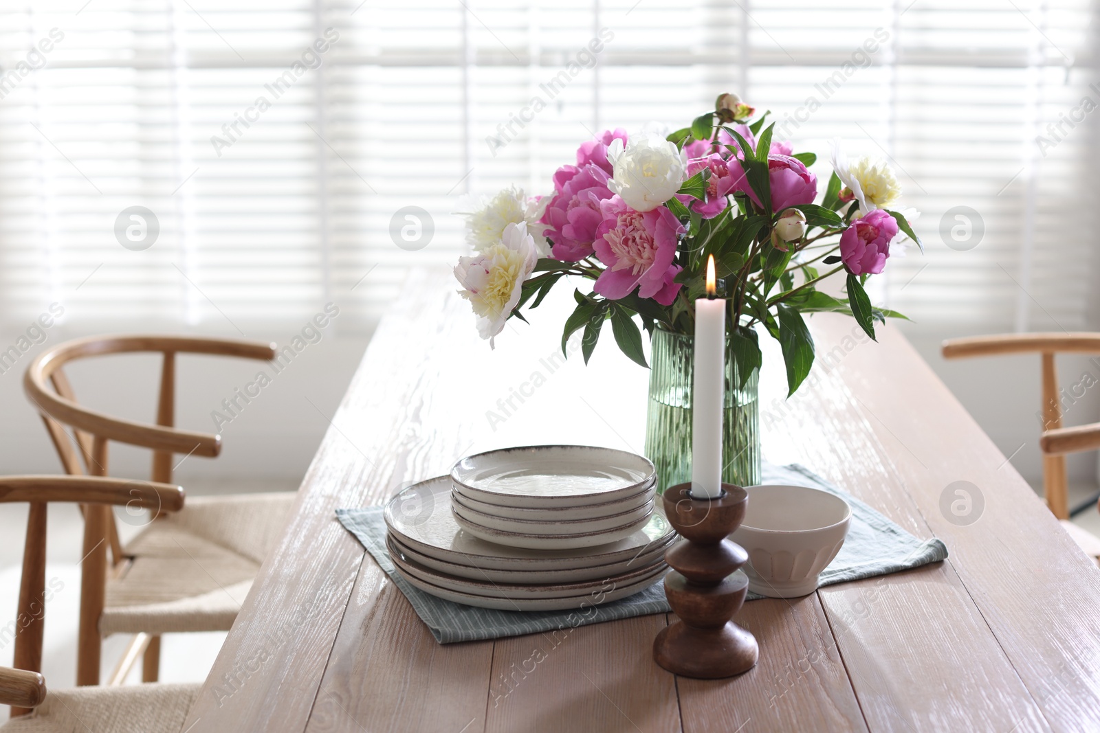 Dining table with beautiful flowers and dishware in room. Interior design Photo of Dining table with beautiful flowers and dishware in room. Interior design