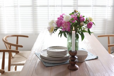 Photo of Dining table with beautiful flowers and dishware in room. Interior design