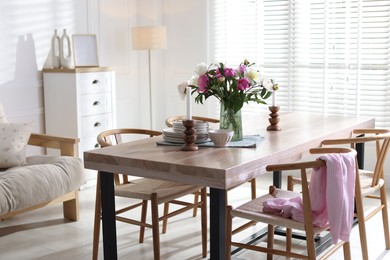 Photo of Dining table with beautiful flowers and dishware in room. Interior design