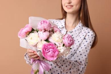 Photo of Woman with beautiful bouquet of peonies on dark beige background, closeup