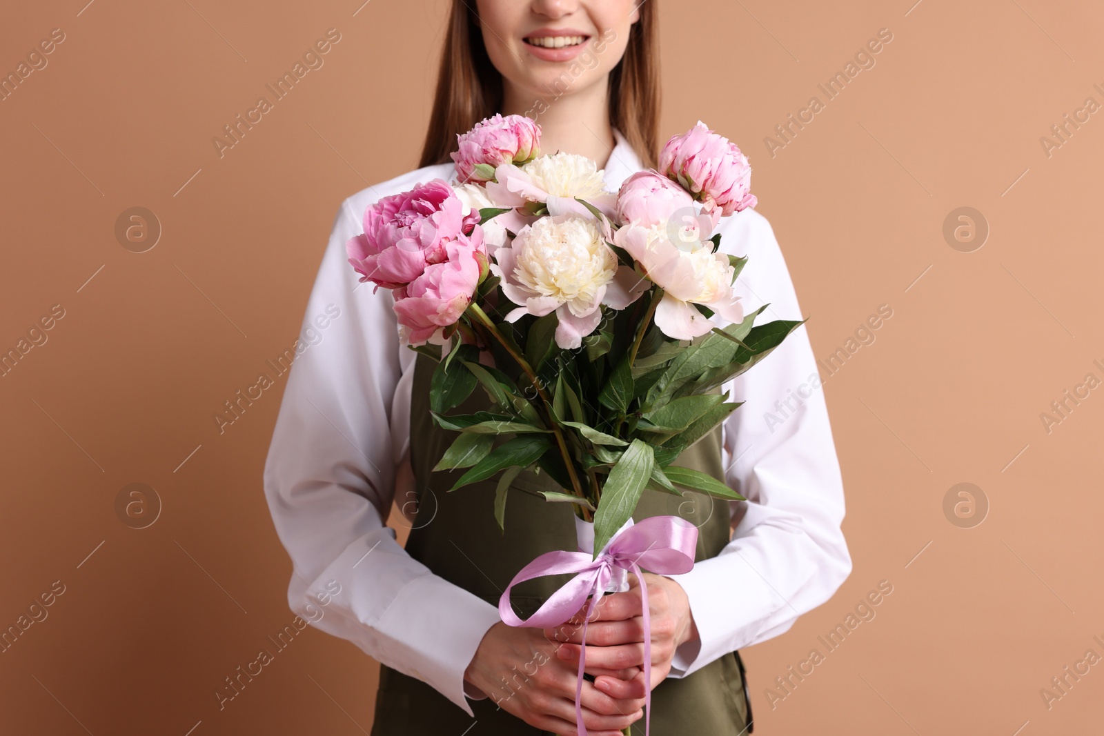Florist with beautiful bouquet of peonies on dark beige background, closeup Photo of Florist with beautiful bouquet of peonies on dark beige background, closeup