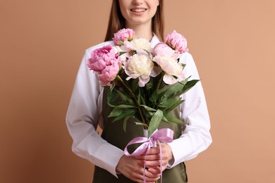Photo of Florist with beautiful bouquet of peonies on dark beige background, closeup