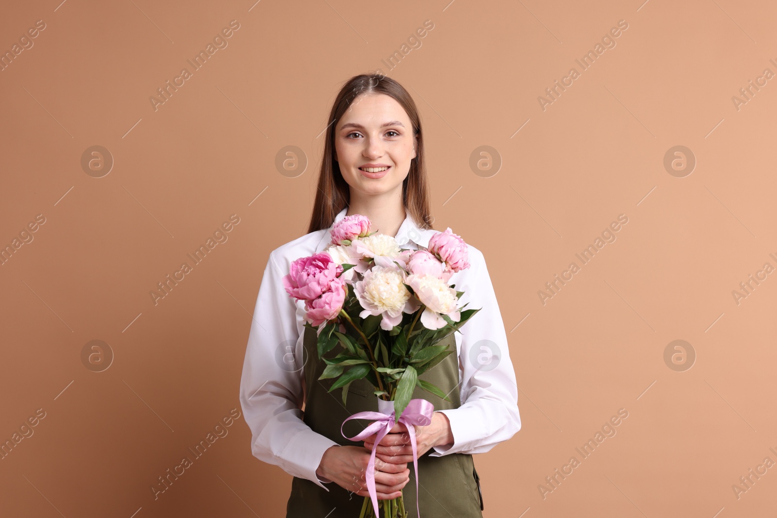 Florist with beautiful bouquet of peonies on dark beige background Photo of Florist with beautiful bouquet of peonies on dark beige background