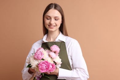 Photo of Florist with beautiful bouquet of peonies on dark beige background