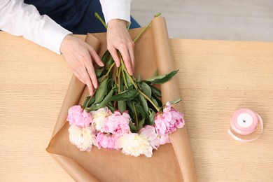 Photo of Florist making bouquet of peonies at wooden table, above view