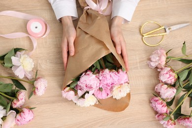 Photo of Florist making bouquet of flowers at wooden table, top view
