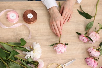 Photo of Florist making bouquet of flowers at wooden table, top view