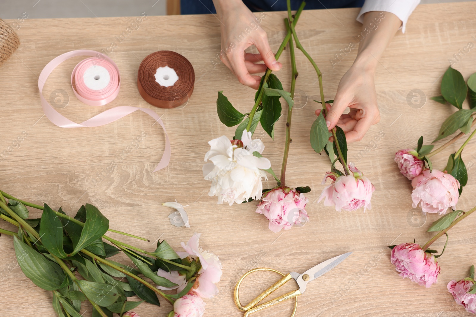 Florist making bouquet of flowers at wooden table, top view Photo of Florist making bouquet of flowers at wooden table, top view