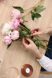 Photo of Florist making bouquet of flowers at wooden table, above view